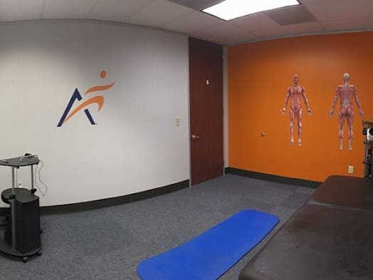 an interior photo of the recovery room at Airrosti Cinco Ranch. a mat on the floor is visible, there are Airrosti decals on the walls.