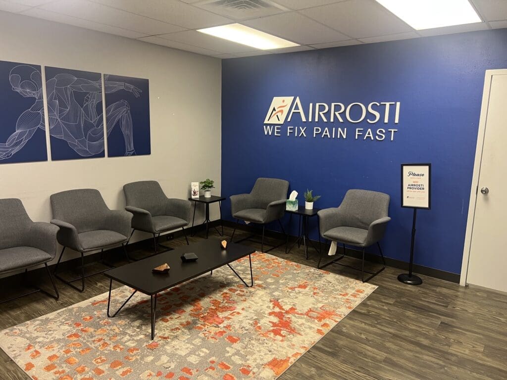 a photo of the lobby at Airrosti Fort Worth. Includes the Airrosti logo on the blue wall.