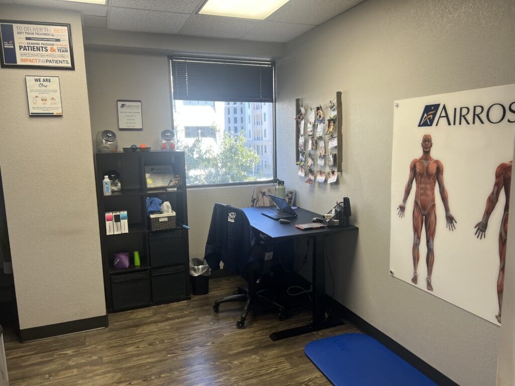 a photo of the interior of a recovery room at Airrosti Fort Worth. Exercise mat, musculoskeletal diagram and K-tape are visible.