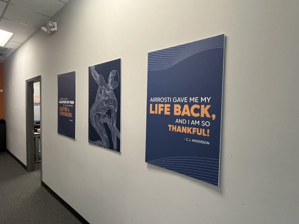 a photo of the hallway at Airrosti Fairfield Village. Airrosti posters are showcased on the wall.