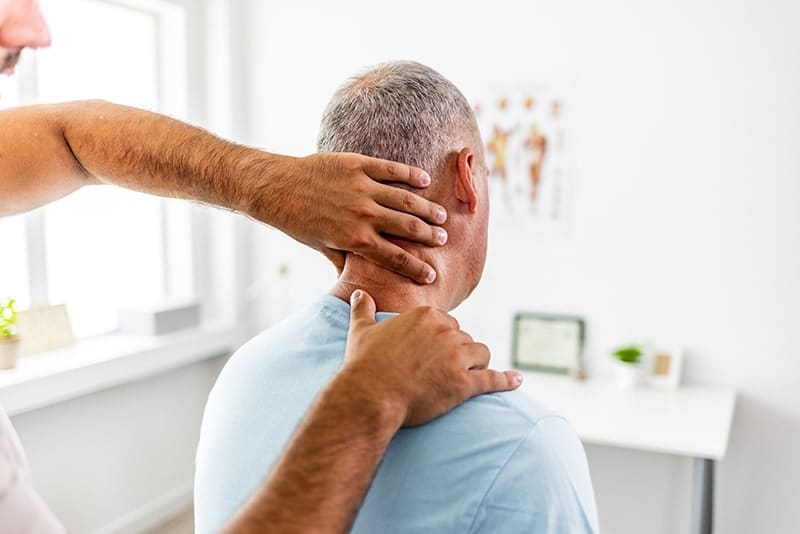 man with neck pain being treated with hands on manual therapy