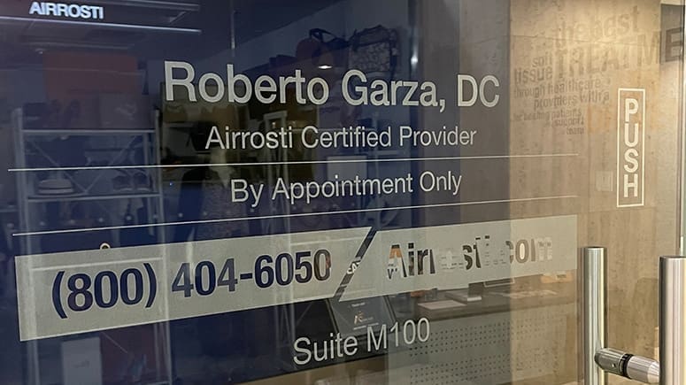 photo of the interior front door of Airrosti Downtown Tunnels. The Airrosti logo, contact info and the providers name is printed on the glass door