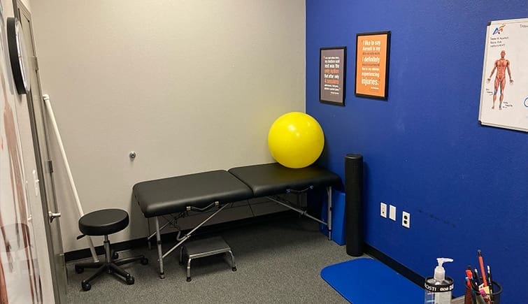 The treatment room at Airrosti Lake Houston showing an exercise ball, exam table, and exercise mat.