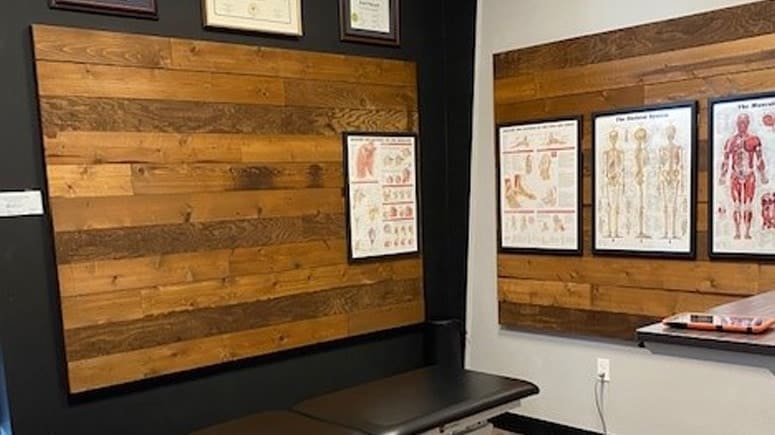 A view of the treatment room inside Airrosti Tacoma, showing a treatment table and posters on the walls of muscle groups and tissue.