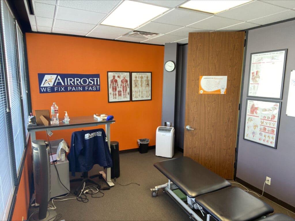 a view of the interior treatment room at Airrosti West U. The providers desk and the treatment table are featured