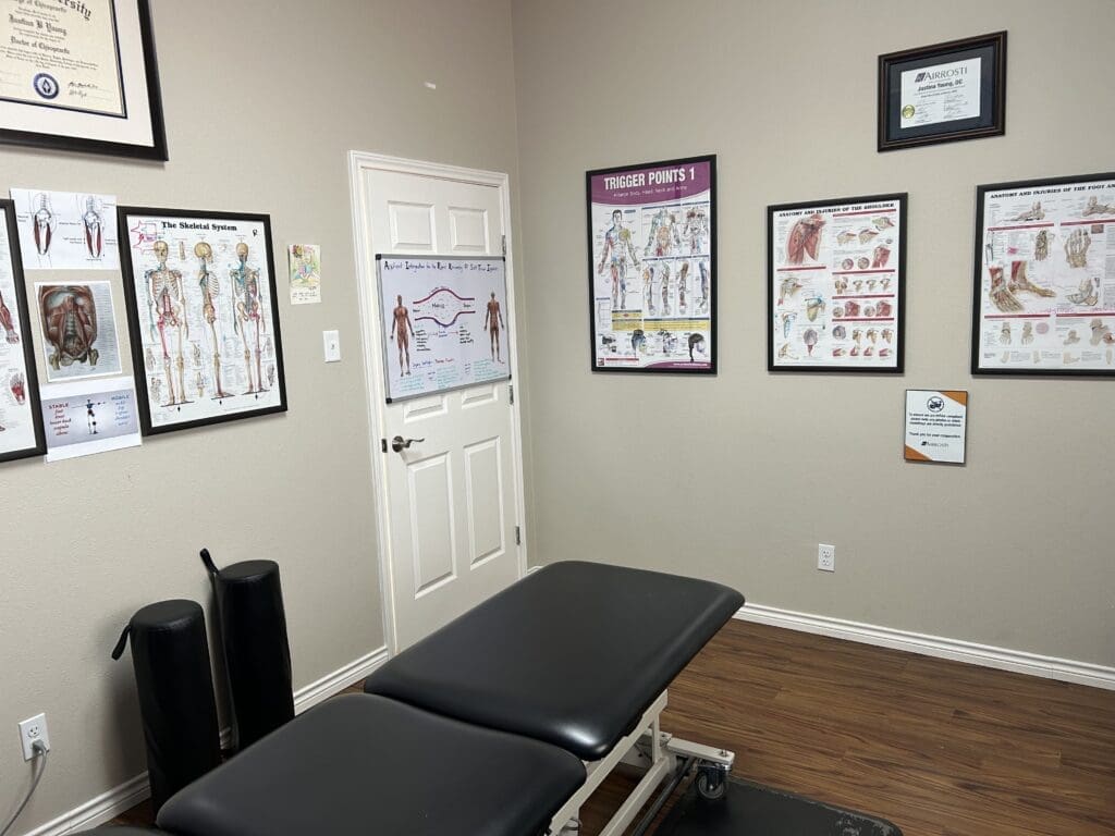 Interview view of treatment room at Airrosti West Fort Worth. MSK posters adorn the walls and treatment table featured in center of the room