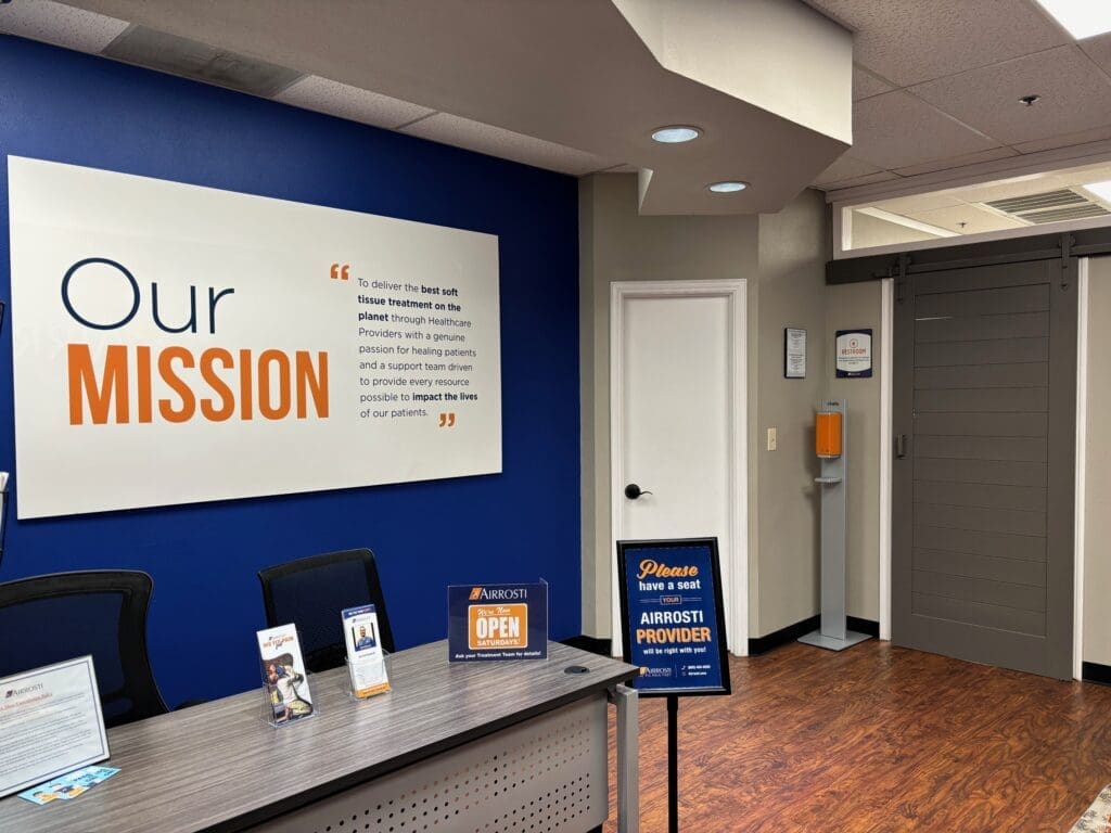 a photo of the lobby at Airrosti Rockwall. The Airrosti mission statement poster decorates the back wall.