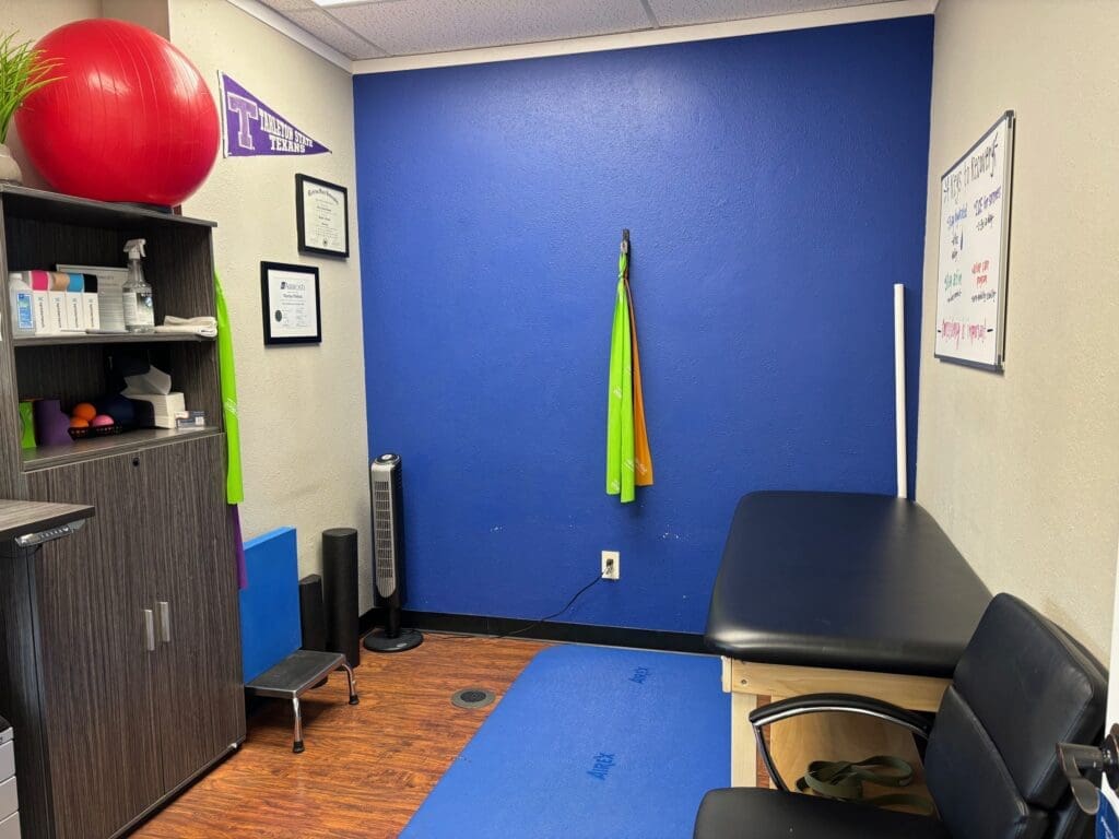 A photo of the recovery room at Airrosti Rockwall. An exercise mat, table and bands are all visible