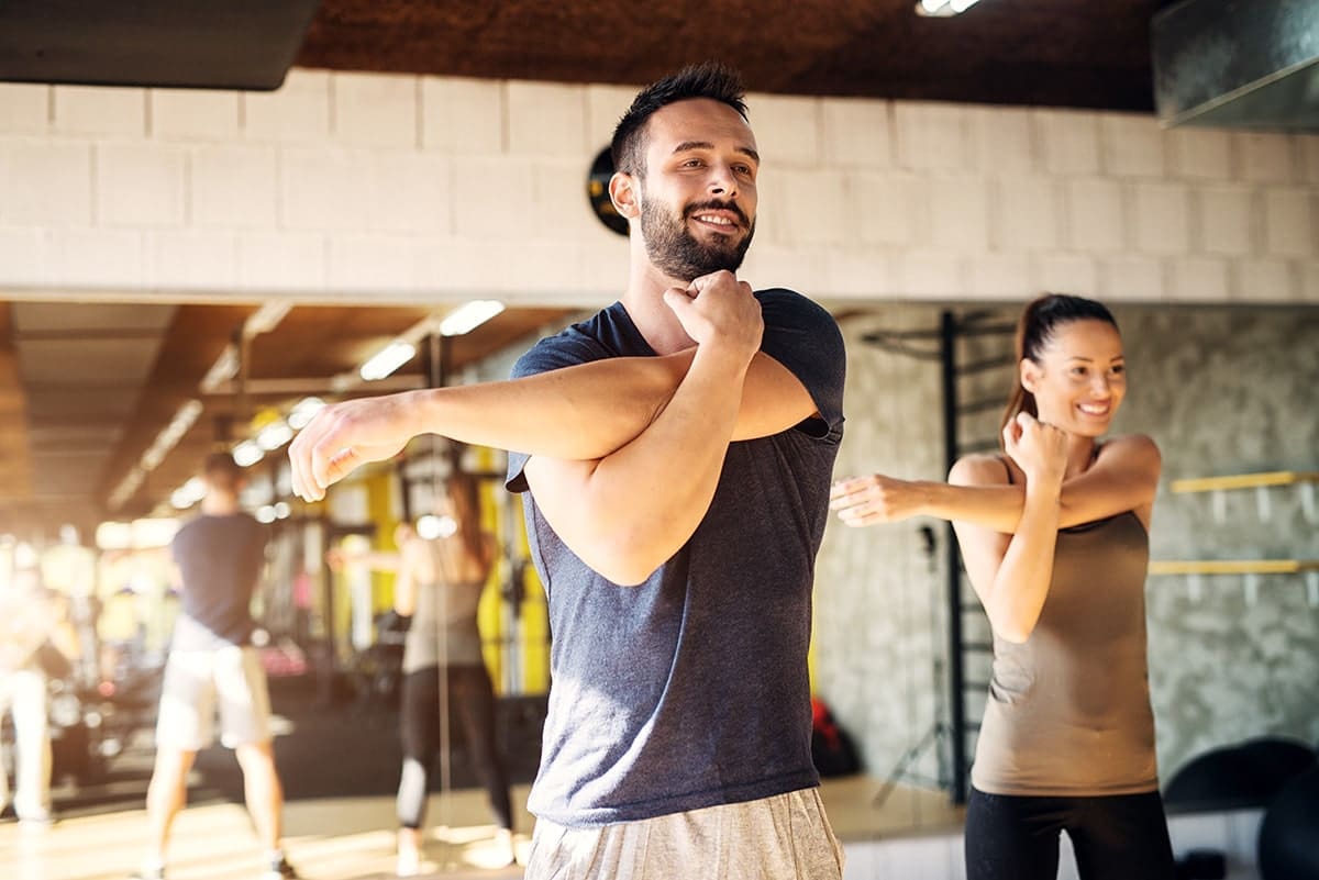 man and woman stretching in the gym