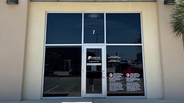 An exterior view of the front entrance to Airrosti Brownsville showing large glass doors and a white number 2 above the entrance.