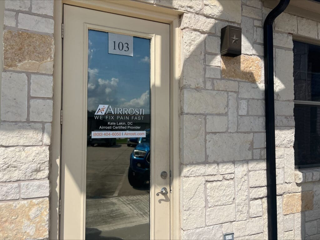 A photo of the exterior door to Airrosti Weatherford. The Airorsti logo and provider information on printed on the glass of the door.