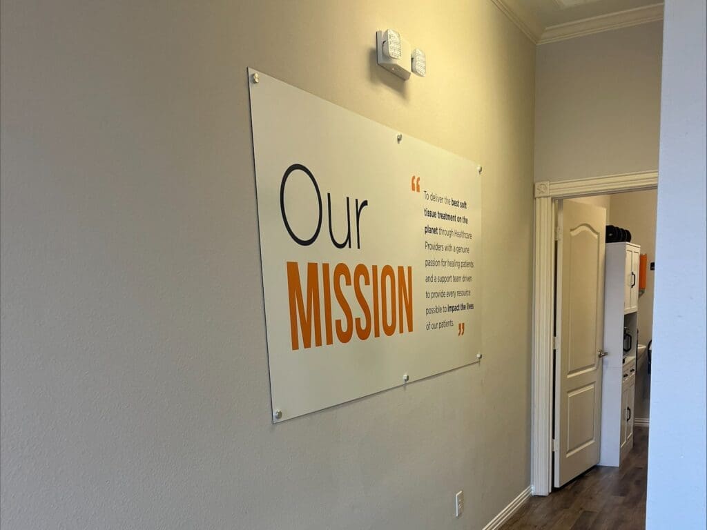 An interior photo of the hallway at Airrosti Weatherford. An Airrosti Our Mission poster decorates the wall.