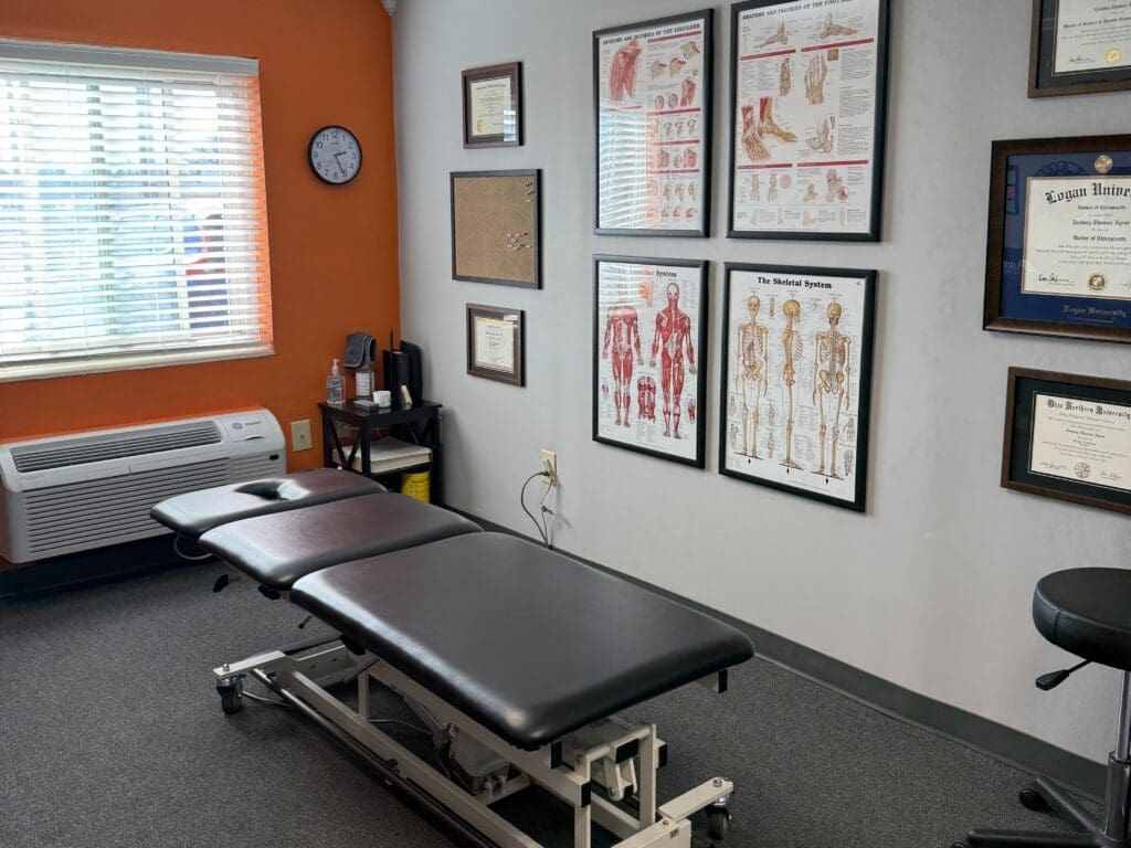 View of the treatment room at Airrosti Beechmont. MSK diagrams adorn the walls. Treatment table featured in the center of the room.,