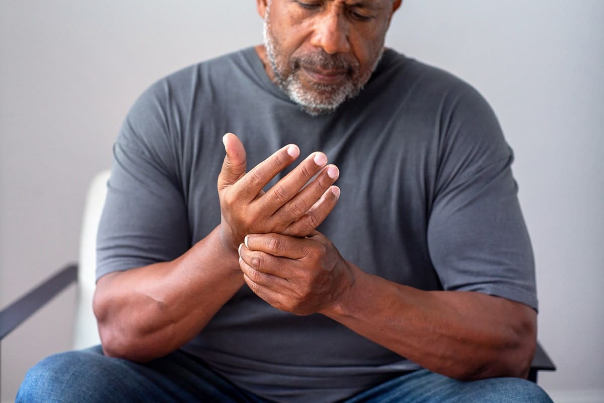 man with arthritis holding wrist in discomfort